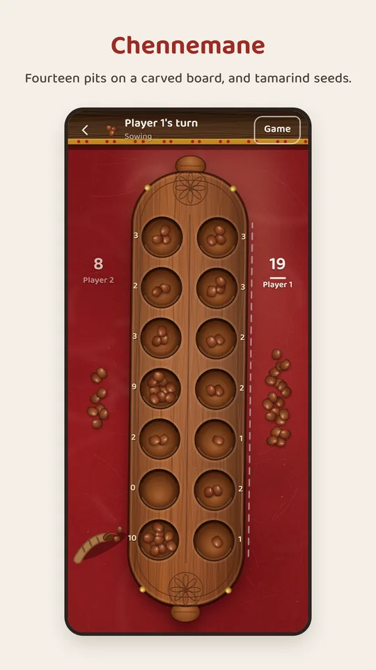 Chennemane: the carved board of fourteen pits, with tamarind seeds, half way through a game.